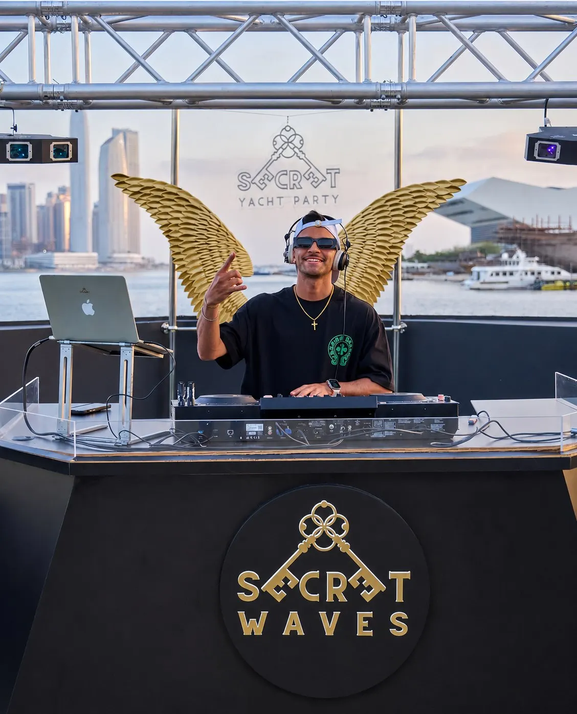 DJ playing behind the Secret Waves booth with the Dubai skyline behind